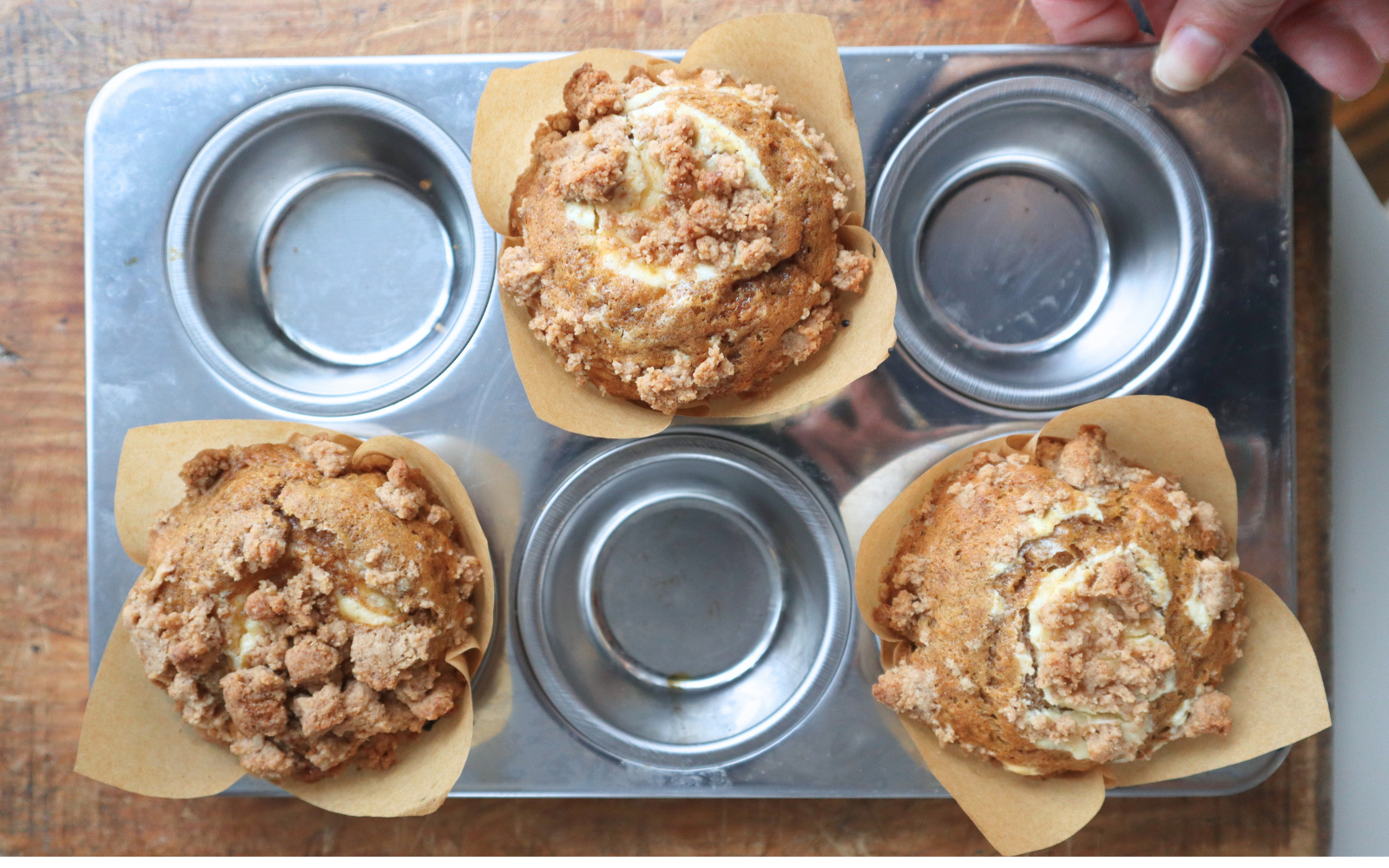 Pumpkin cream cheese muffins with cinnamon crumb topping, one split open to show the cheesecake centre